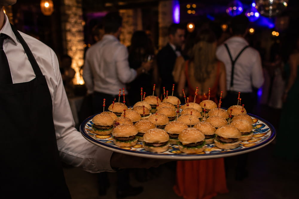Waiter serving mini burgers as part of the recena of a Spanish wedding