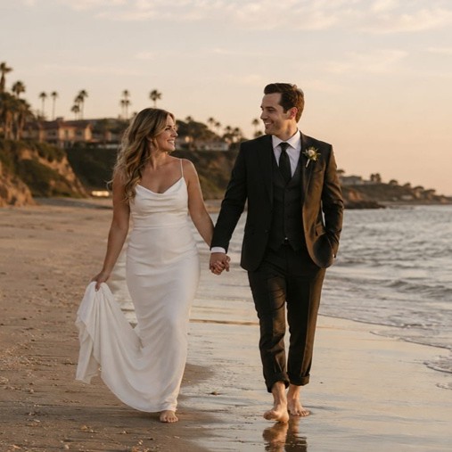 Bride and groom walking on the beach at sunset