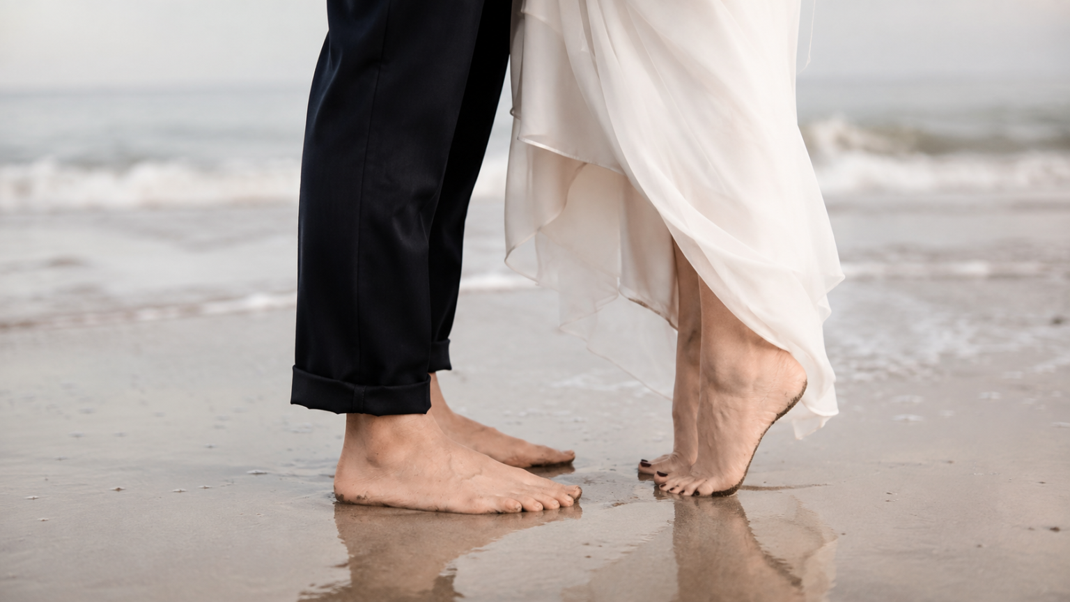 Feet of groom and bride touching the sand