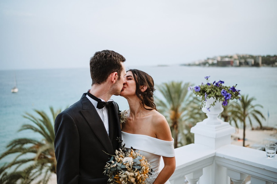 Photo of groom and bride kissing with the Mediterranean sea in the background